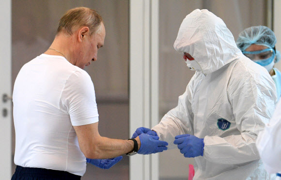 블라디미르 푸틴 러시아 대통령이 24일(현지시간) 신종 코로나바이러스 감염증(코로나19) 환자들이 입원해 있는 모스크바 남쪽 코무나르카 지역의 한 병원을 방문한 후 보호 장갑을 벗고 있다. EPA 연합뉴스