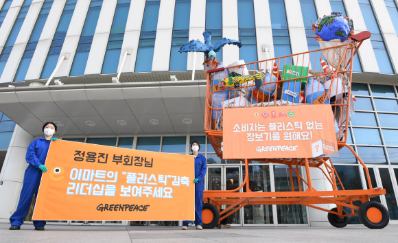 26일 서울 성수동 이마트 본사 앞에서 그린피스가 플라스틱 쓰레기로 가득 찬 높이 5m짜리 대형 카트를 설치해 퍼포먼스를 하고 있다. 그린피스 서울사무소는 지난 2월 18일부터 ‘플라스틱 문제 해결을 위해 나서줬으면 하는 마트’를 선정하는 온라인 시민 투표를 진행했다. 그 결과 이마트, 홈플러스, 롯데마트, 하나로마트, 메가마트 등 5대 대형마트 중 이마트가 58%의 득표율로 1위로 선정되었다. 그린피스는 불필요한 일회용 플라스틱 포장재를 없애기 위해, 국내 대형마트에 플라스틱 감축 목표를 세우고 이를 투명하게 공개할 것을 요구했다. 2020.3.26. 오장환 기자 5zzang@seoul.co.kr