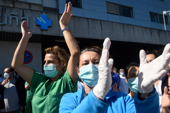 스페인 라 코루냐의 한 병원 밖에서 26일(현지시간) 신종 코로나바이러스 감염증(코로나19) 의료진이 박수를 보내는 주민과 경찰들에게 화답하고 있다. 이날 스페인 내 코로나19 사망자 수는 전날보다 655명 증가해 총 4천 명을 넘어섰다. 라코루냐 AFP 연합뉴스