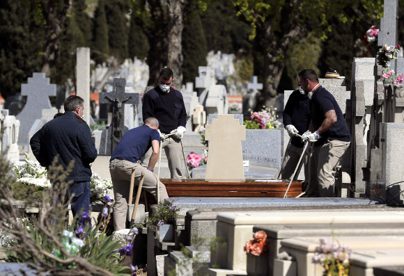 26일(현지시간) 스페인 마드리드 외곽의 한 공동묘지에는 코로나19 희생자들의 시신을 옮기고 있다. 마드리드 AP 연합뉴스