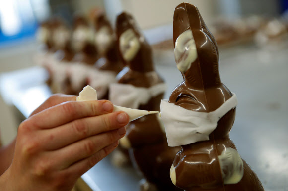 세계적으로 신종 코로나바이러스(코로나19)의 확산이 계속되고 있는 가운데 27일(현지시간) 스위스 베른에 있는 한 베이커리에서 마스크를 쓴 부활절 토끼 초콜릿을 만들고 있다.  AFP 연합뉴스