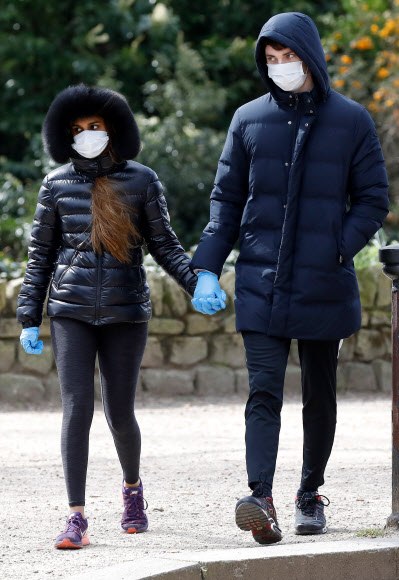 영국 런던의 배터시 공원에서 28일(현지시간) 마스크를 쓰고 장갑까지 낀 남녀가 손을 맞잡고 하루 한 번 밖에 허용되지 않는 바깥 활동을 즐기고 있다. 런던 AFP 연합뉴스 