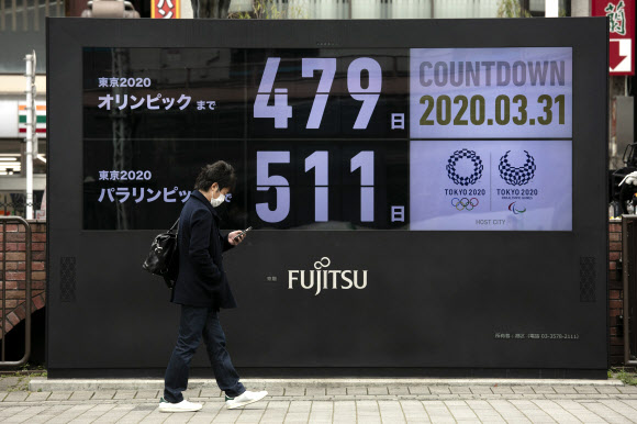 내년으로 연기된 도쿄올림픽 개막이 7월 23일로 확정된 이튿날인 31일 일본 도쿄 시내에 설치된 올림픽 카운트다운 전광판 앞으로 한 시민이 마스크를 쓴 채 지나가고 있다. 전광판은 새 일정에 따라 도쿄올림픽이 479일 남았다고 알리고 있다. AP 연합뉴스