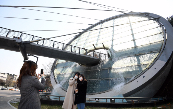 2일 서울 서초구 예술의전당에서 양재역 방면에 있는 아쿠아아트육교의 워터스크린 앞에서 시민들이 사진을 찍고 있다. 워터스크린은 10월 말까지 출근, 점심, 퇴근시간대에 가동한다. 2020.4.2  박윤슬 기자 seul@seoul.co.kr