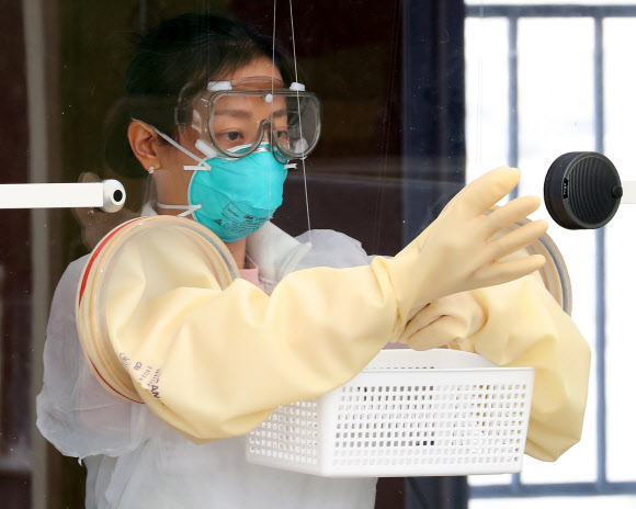 3일 오후 서울 송파구 잠실종합운동장에 마련된 워크스루 방식 선별진료소에서 한 의료진이 진료소 개시 전 준비하기 위해 장갑을 끼워보고 있다. 2020.4.3  연합뉴스