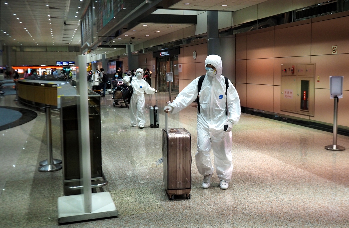 대만 타이베이 북부의 타오위안 국제공항에서 23일(현지시간) 한 남녀가 코로나19 감염을 막기 위해 방호복을 입은 채 캐리어를 끌고 어딘가로 향하고 있다. 2020.3.23  EPA 연합뉴스