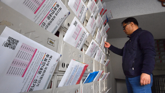 투표안내문과 선고공보가 유권자에게 배송된 5일 서울 마포구의 한 아파트에서 시민이 우편물을 살펴보고 있다. 2020.4.5 박지환기자 popocar@seoul.co.kr