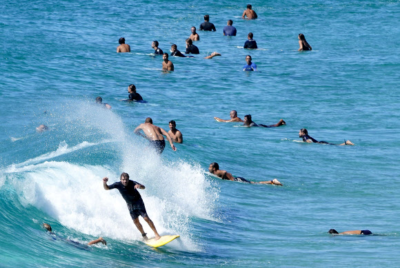 코로나19 확산으로 이동제한 명령이 내려진 가운데 6일(현지시간) 호주 퀸즐랜드주 골드코스트 바닷가에 많은 사람들이 서핑을 즐기고 있다. EPA 연합뉴스