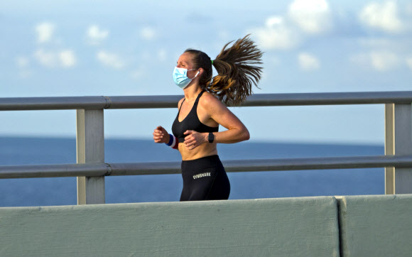 코로나19 확진자가 늘고 있는 가운데 한 여성이 5일(현지시간) 미국 플로리다주 리켄배커 코즈웨이를 달리고 있다. AP 연합뉴스