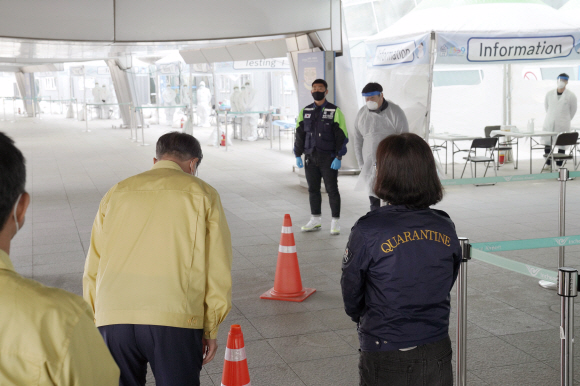 문재인 대통령이 7일 인천국제공항 제1터미널에 마련된 코로나19 개방형 선별진료소(오픈 워크 스루·Open Walk Thru)를 찾아 진료소 근무자들을 향해 인사하고 있다. 2020.4.7  청와대 제공