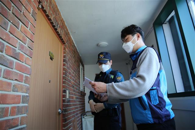 자가격리자 점검 사진 (해당 기사와 직접적 관련 없음)  지난 3일 서울 관악구 직원(오른쪽)과 경찰이 한 자가격리자의 자택을 방문해 불시 점검하고 있다. 관악구 제공