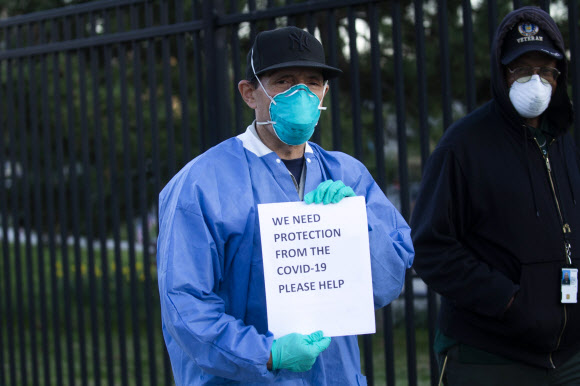 지난 6일(현지시간) 미국 뉴욕시의 브룩클린에 있는 VA 메디컬센터 간호사들이 교대시간을 틈타 의료용 마스크 등 개인보호장비(PPE)의 원활한 지원을 요구하는 포스터를 들어 보이고 있다. 뉴욕 AFP 연합뉴스 