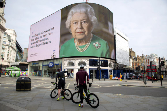 8일(이하 현지시간) 영국 런던의 피카딜리 서커스 광고판에 사흘 전 엘리자베스 2세 여왕의 대국민 연설 발언 “더 나은 나날이 돌아올 것”이 게재돼 사이클을 타고 지나가던 이들이 멈춰 서 보고 있다. 런던 AP 연합뉴스 