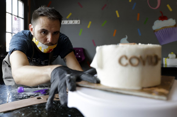 미국 시카고에 있는 ‘팁시 스페이스’의 파티셰 팀 바르다가 8일(현지시간) 화장실 휴지 모양으로 만들어 코로나19 시대를 풍자한 생일 케이크 만드느라 열중하고 있다. 　시카고 AP 연합뉴스