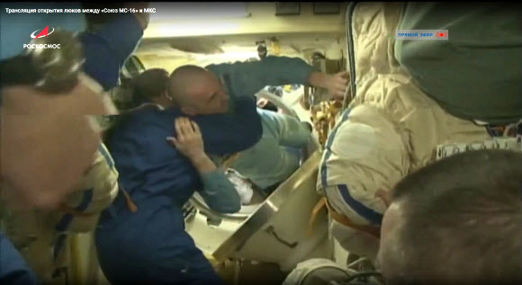 9일(현지시간) 카자흐스탄 바이코누르 우주기지에서 발사된 러시아 소유스 MS-16 유인우주선에 실려 국제우주정거장(ISS)에 도킹한 러시아 우주인 아나톨리 이바니신이 해치를 통해 들어서자 ISS에 머무르던 우주인이 격하게 끌어안고 있다. 로스코스모스 동영상 캡처 EPA 연합뉴스