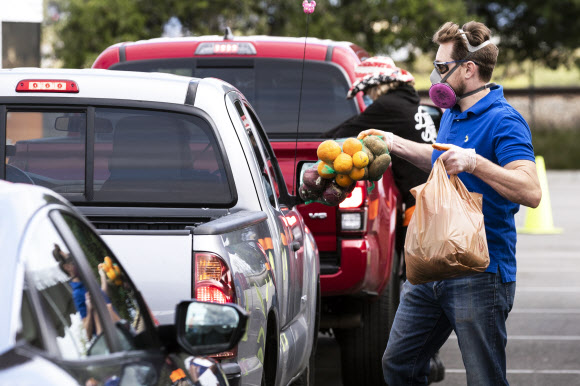 미국 로스앤젤레스 애너하임 혼다센터에서 자원봉사자들이 드라이브 스루 방식으로 음식을 자동차 트렁크나 뒷좌석에 실어 주고 있다.  로스앤젤레스 EPA 연합뉴스