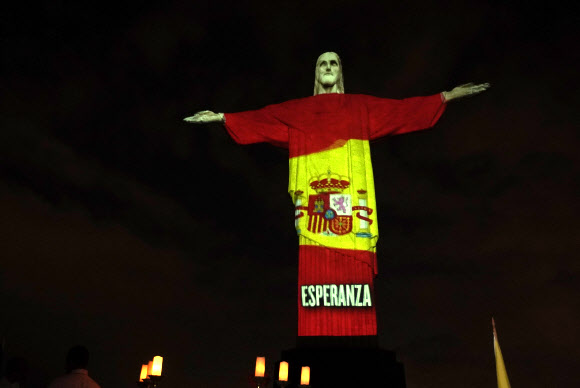 12일(현지시간) 브라질 리우데자네이루의 예수상에 부활절을 맞아 신종 코로나바이러스 감염증(코로나19)과 싸우고 있는 각국의 국기가 비치고 있다. AP 연합뉴스