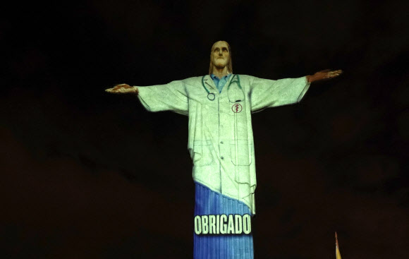 12일(현지시간) 브라질 리우데자네이루의 예수상에 부활절을 맞아 신종 코로나바이러스 감염증(코로나19)과 싸우고 있는 각국의 국기가 비치고 있다. AP 연합뉴스