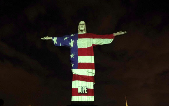 12일(현지시간) 브라질 리우데자네이루의 예수상에 부활절을 맞아 신종 코로나바이러스 감염증(코로나19)과 싸우고 있는 각국의 국기가 비치고 있다. AP 연합뉴스