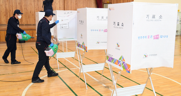 ‘제21대 국회의원 선거’를 하루 앞둔 14일 오후 서울 종로구 청운초등학교 체육관에서 관계자들이 투표소 설치를 마친 뒤 방역하고 있다. 2020. 4. 14  박윤슬 기자 seul@seoul.co.kr