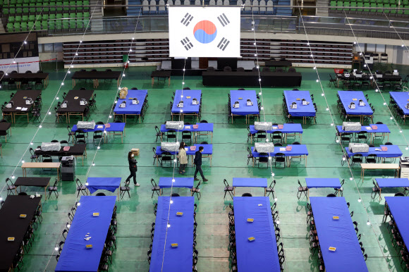 4.15 총선 투표일을 하루 앞둔 14일 오후 대구시 북구 산격동 대구체육관에 마련된 개표소에 지난 총선보다 길어진 수작업 개표용 탁자가 설치돼 있다. 이번 선거는 비례대표 선출을 위한 정당투표의 경우 투표지 길이가 48.1㎝에 달해 손으로 개표를 진행한다. 태극기는 뒷면의 모습이다. 2020.4.14  연합뉴스