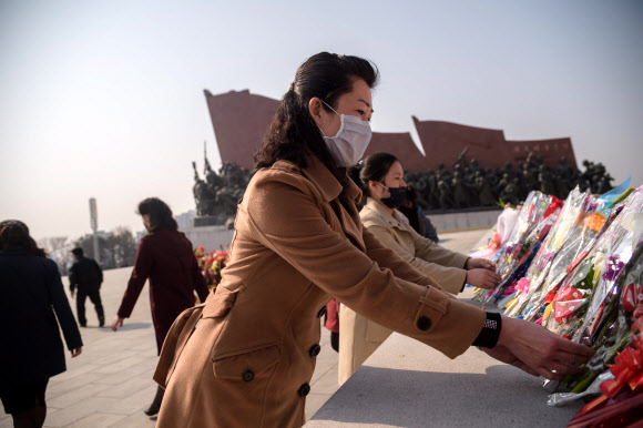 마스크를 쓴 평양 시민이 15일 108번째 김일성 주석의 생일을 맞아 꽃을 김일성 동상에 바치고 있다. 연합뉴스