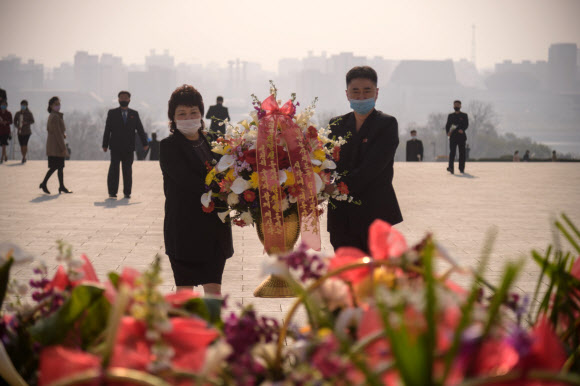 마스크를 쓴 평양 시민들이 15일 김일성 주석의 108회 생일인 태양절을 맞아 김일성 주석의 동상에 헌화하고 있다. AFP 연합뉴스