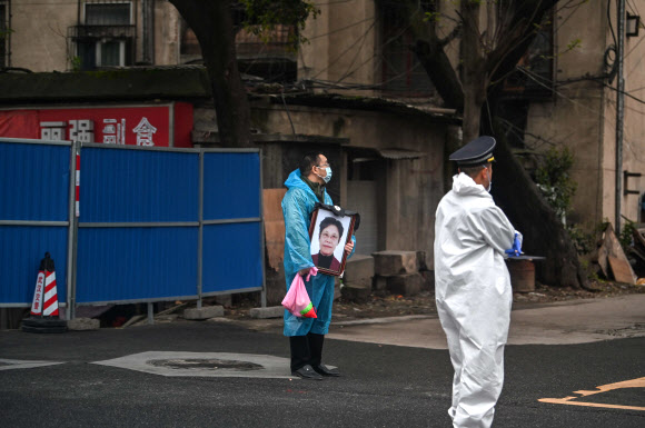 지난 1일 중국 코로나19 발병의 진원지인 후베이성 우한의 비안단산 묘원에서 마스크를 쓴 한 시민이 초상화를 들고 서 있다. 우한 AFP 연합뉴스