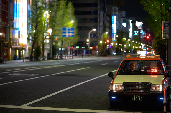 일본 택시 운전사가 17일 코로나19 확산 여파로 텅 빈 도쿄의 아키하바라 구역에서 손님을 기다리고 있다. 도쿄 AFP 연합뉴스 