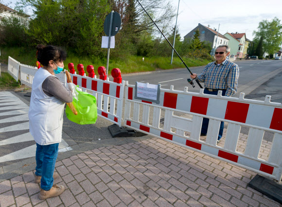 한 독일 시민이 18일(현지시간) 독일과 프랑스 국경에서 코로나 19 감염의 확산을 억제하기 위한 프랑스의 봉쇄에, 벌금을 피하기 위해서 낚시대를 이용해서 프랑스 바게트를 받고 있다. AFP 연합뉴스