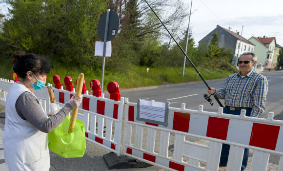 한 독일 시민이 18일(현지시간) 독일과 프랑스 국경에서 코로나 19 감염의 확산을 억제하기 위한 프랑스의 봉쇄에, 벌금을 피하기 위해서 낚시대를 이용해 프랑스 바게트를 받고 있다. AFP 연합뉴스