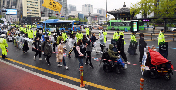 장애인의 날인 20일 서울 광화문 광장에서 전국장애인차별철폐연대 활동가들이 집단수용 장애인 거주시설 폐쇄와 장애등급제 폐지 등 요구사항을 적은 피켓을 목에 걸고 대학로 방향으로 행진하고 있다. 2020.4.20 박윤슬 기자 seul@seoul.co.kr