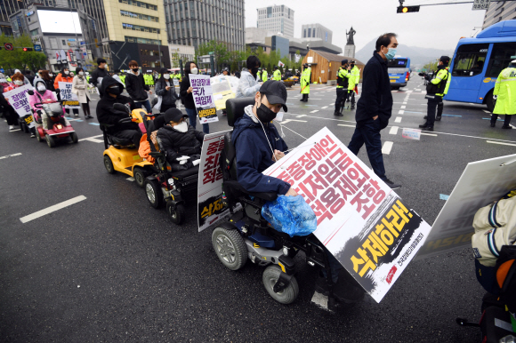장애인의 날인 20일 서울 광화문 광장에서 전국장애인차별철폐연대 활동가들이 집단수용 장애인 거주시설 폐쇄와 장애등급제 폐지 등 요구사항을 적은 피켓을 목에 걸고 대학로 방향으로 행진하고 있다. 2020.4.20 박윤슬 기자 seul@seoul.co.kr