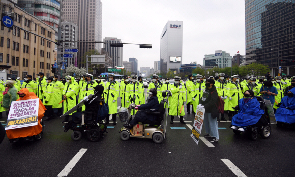 장애인의 날인 20일 서울 광화문 광장에서 전국장애인차별철폐연대 활동가들이 집단수용 장애인 거주시설 폐쇄와 장애등급제 폐지 등 요구사항을 적은 피켓을 목에 걸고 대학로 방향으로 행진하고 있다. 2020.4.20 박윤슬 기자 seul@seoul.co.kr