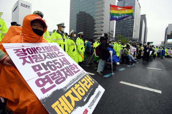 장애인의 날인 20일 서울 광화문 광장에서 전국장애인차별철폐연대 활동가들이 집단수용 장애인 거주시설 폐쇄와 장애등급제 폐지 등 요구사항을 적은 피켓을 목에 걸고 대학로 방향으로 행진을 준비하고 있다. 2020.4.20 박윤슬 기자 seul@seoul.co.kr