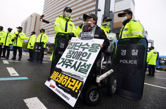 장애인의 날인 20일 서울 광화문 광장에서 전국장애인차별철폐연대 활동가들이 집단수용 장애인 거주시설 폐쇄와 장애등급제 폐지 등 요구사항을 적은 피켓을 목에 걸고 대학로 방향으로 행진을 준비하고 있다. 2020.4.20 박윤슬 기자 seul@seoul.co.kr