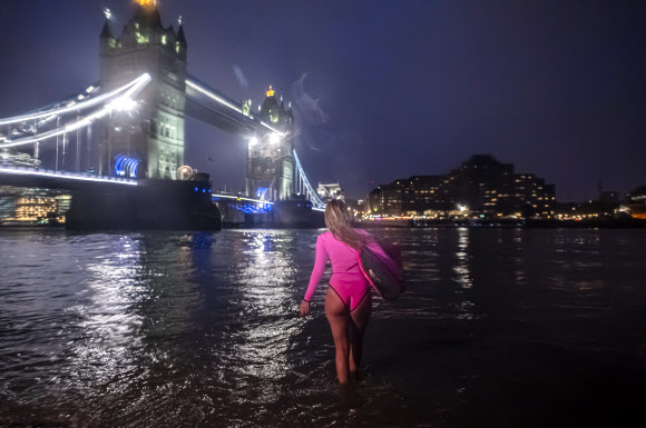 하와이의 ‘시위 서퍼’ 앨리슨 틸이 기후변화에 대처할 필요성에 대한 인식을 높이기 위해 3월 5일 런던을 방문했을 때, 서핑보드를 들고 템즈강으로 들어가고 있다. 앨리슨 틸은 멕시코의 폐수에 태클 후, 파리의 센 강과 몰디브의 쓰레기 섬을 패들링하며 환경에 대한 인식을 높이기 위해 분홍색 ‘에코 친화적인’ 서핑보드로 세계를 여행하고 있다. AFP 연합뉴스