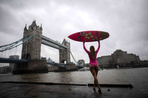 하와이의 ‘시위 서퍼’ 앨리슨 틸이 기후변화에 대처할 필요성에 대한 인식을 높이기 위해 3월 5일 런던을 방문했을 때, 템즈강에서 서핑보드를 들고 있다. 앨리슨 틸은 멕시코의 폐수에 태클 후, 파리의 센 강과 몰디브의 쓰레기 섬을 패들링하며 환경에 대한 인식을 높이기 위해 분홍색 ‘에코 친화적인’ 서핑보드로 세계를 여행하고 있다. AFP 연합뉴스