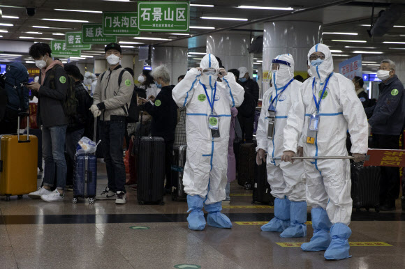 지난 19일 중국 베이징역에서 보호복을 입은 요원들이 고속열차를 타고 도착한 승객들을 대상으로 발열검사 등을 하기 위해 기다리고 있다. 베이징 AP 연합뉴스