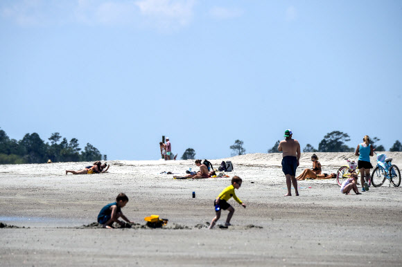 사람들이 25일(현지시간) 조지아 타이비 아일랜드의 타이비 해변에서 휴식을 취하고 있다. 타이비 아일랜드 시의회는 3월 20일 해변을 폐쇄하는 투표를 했다. 그러나 브라이언 켐프 조지아 주지사는 코로나바이러스와 관련된 모든 지역 명령을 대체하는 주 전역의 쉼터-인-플레이스(shelter-in-place) 행정 명령을 내리고 주의 해변을 개방했다. AFP 연합뉴스
