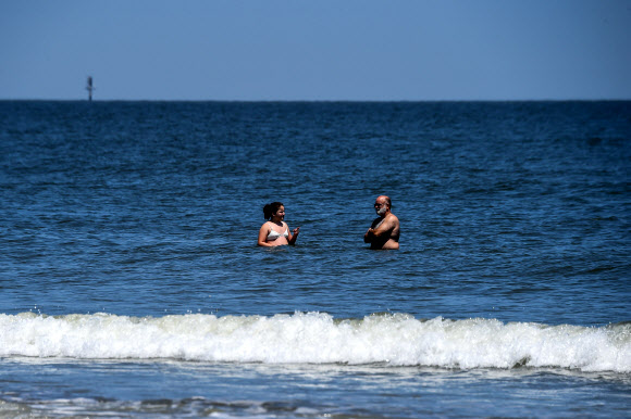 한 커플이 25일(현지시간) 조지아 타이비 아일랜드의 타이비 해변에서 휴식을 취하고 있다. 타이비 아일랜드 시의회는 3월 20일 해변을 폐쇄하는 투표를 했다. 그러나 브라이언 켐프 조지아 주지사는 코로나바이러스와 관련된 모든 지역 명령을 대체하는 주 전역의 쉼터-인-플레이스(shelter-in-place) 행정 명령을 내리고 주의 해변을 개방했다. AFP 연합뉴스