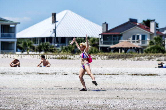 한 여성이 25일(현지시간) 조지아 타이비 아일랜드의 타이비 해변에서 춤을 추고 있다. 타이비 아일랜드 시의회는 3월 20일 해변을 폐쇄하는 투표를 했다. 그러나 브라이언 켐프 조지아 주지사는 코로나바이러스와 관련된 모든 지역 명령을 대체하는 주 전역의 쉼터-인-플레이스(shelter-in-place) 행정 명령을 내리고 주의 해변을 개방했다. AFP 연합뉴스