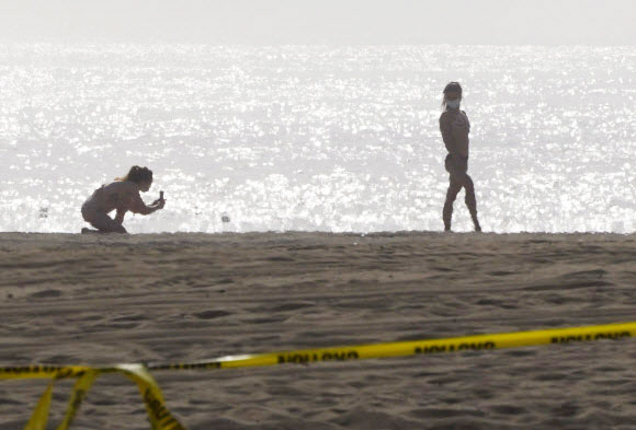 두 여성이 25일(현지시간) 미국 캘리포니아주 베니스 해변에서 코로나바이러스 유행 속, 서로 사진을 찍고 있다. AP 연합뉴스
