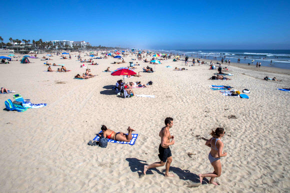 사람들이 25일(현지시간) 미국 캘리포니아주 헌팅턴 비치에서 코로나-19 유행 속, 해변에서 즐거운 시간을 보내고 있다. AFP 연합뉴스