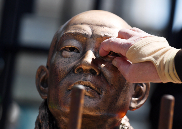 ‘사자(死者) 명예훼손’ 혐의로 기소된 전두환 씨가 법정에 출석하는 27일 광주 동구 광주지법 앞에서 오월 어머니회 회원이 무릎 꿇은 전두환 동상의 눈을 파내는 시늉을 하고 있다. 2020. 4. 27. 박윤슬 기자 seul@seoul.co.kr