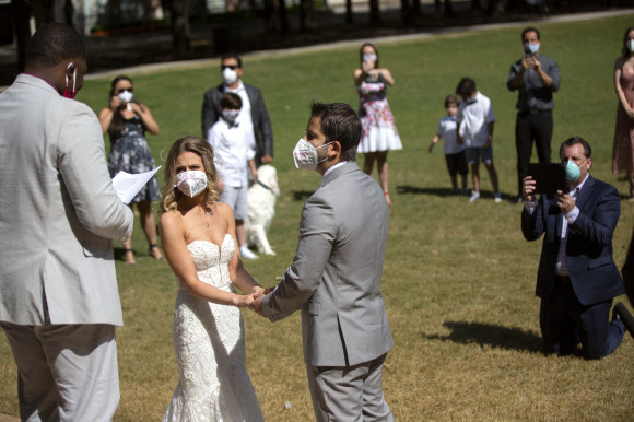 27일(현지시간) 미국 텍사스주 휴스턴의 한 공원에서 결혼식이 열리고 있다. 신종 코로나바이러스 감염증(코로나19) 확산으로 이날 신랑, 신부를 비롯한 하객들은 마스크를 쓰고 참석한 가운데 결혼식이 진행됐다. AP 연합뉴스