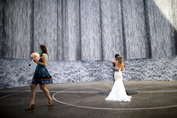 27일(현지시간) 미국 텍사스주 휴스턴의 한 공원에서 결혼식이 열리고 있다. 신종 코로나바이러스 감염증(코로나19) 확산으로 이날 신랑, 신부를 비롯한 하객들은 마스크를 쓰고 참석한 가운데 결혼식이 진행됐다. AP 연합뉴스