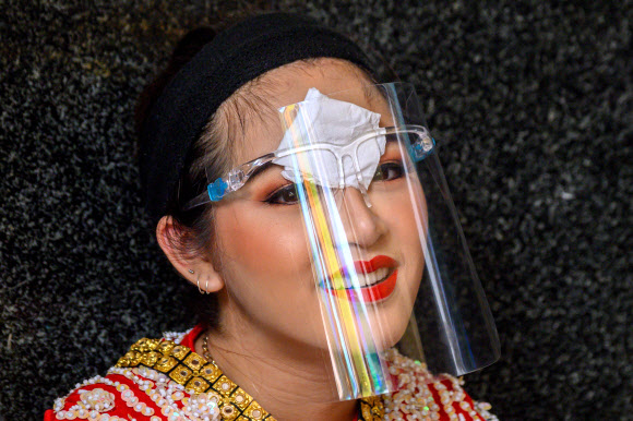 태국 전통 무용수가 3일(현지시간) 방콕 에라완 사원에서 코로나19 에방용 얼굴 보호구를 착용하고 있다. AFP 연합뉴스