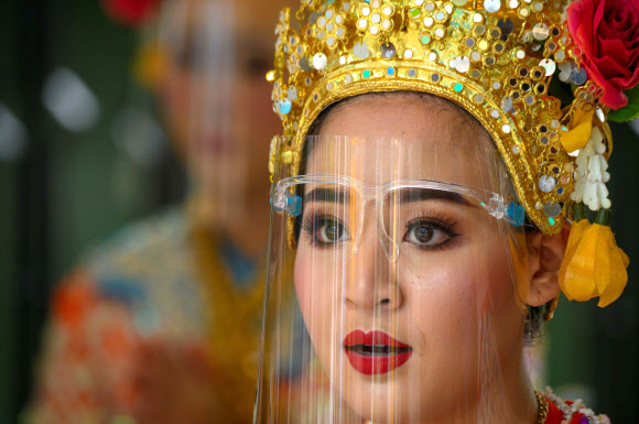 태국 전통 무용수가 3일(현지시간) 방콕 에라완 사원에서 코로나19 에방용 얼굴 보호구를 착용하고 있다. AFP 연합뉴스