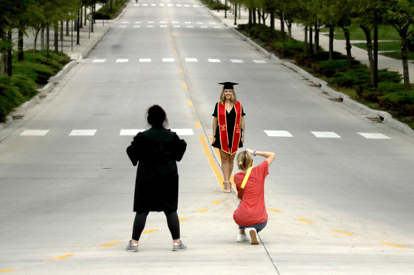 지난달 26일(현지시간) 미국 캔자스대에서 한 졸업생이 텅 빈 교정에서 사진을 찍고 있다. AP통신